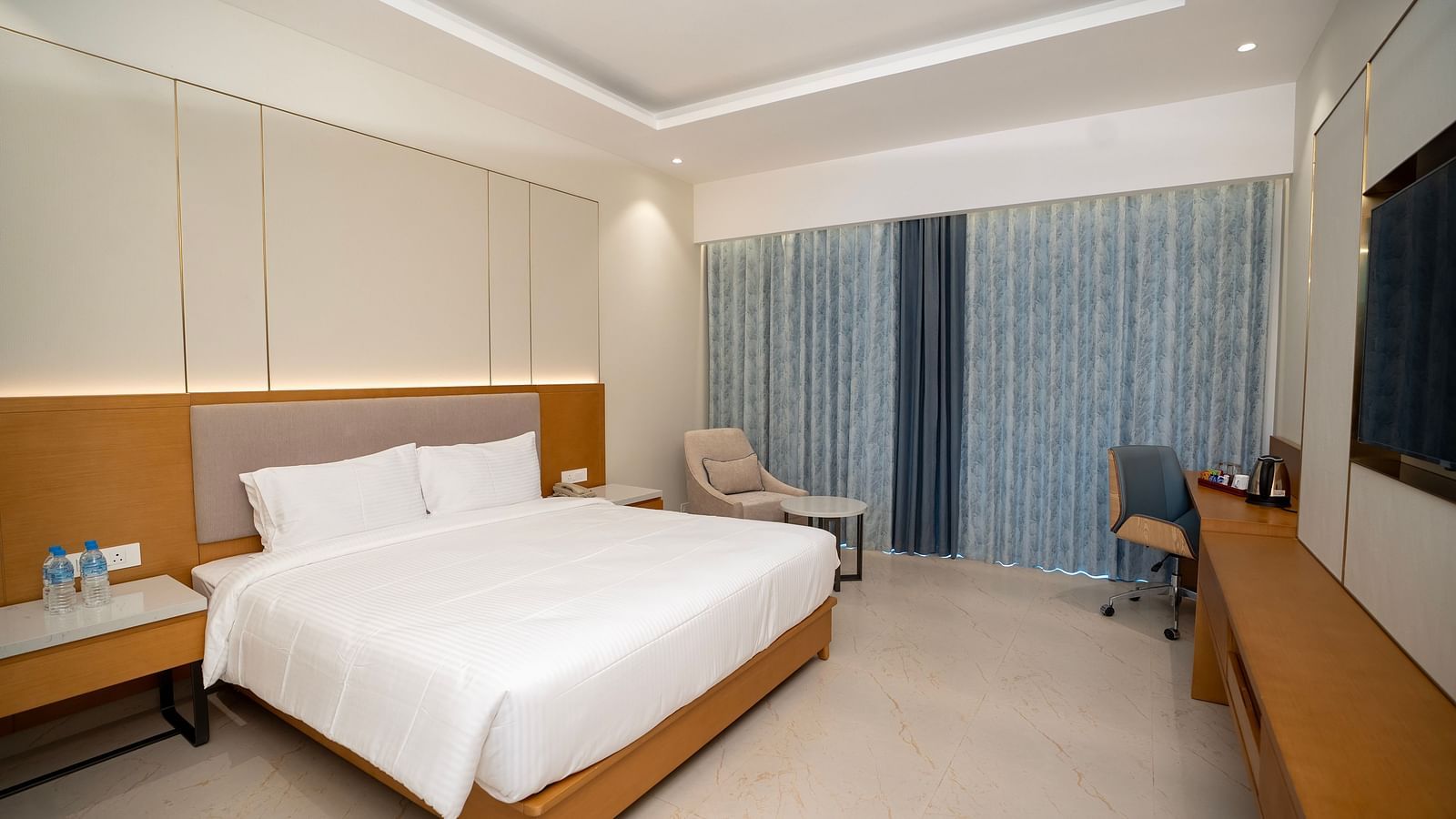 Corner view shot of the Bay View Bliss room with pastel blue curtains covering the window at The Shore, Trishvam.