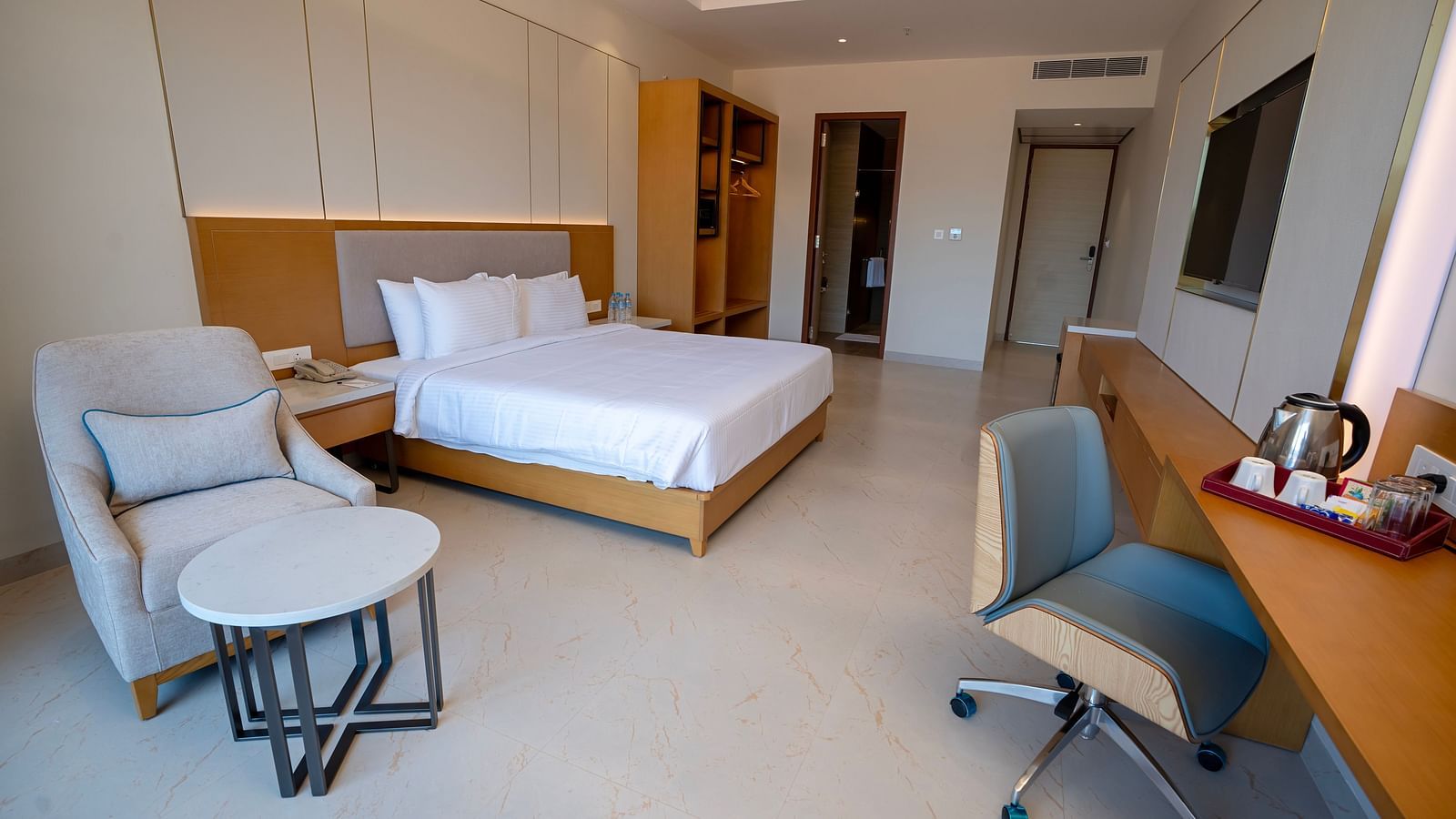 Full view shot of the Bay View Bliss room featuring a double bed along with an armchair and a work desk.