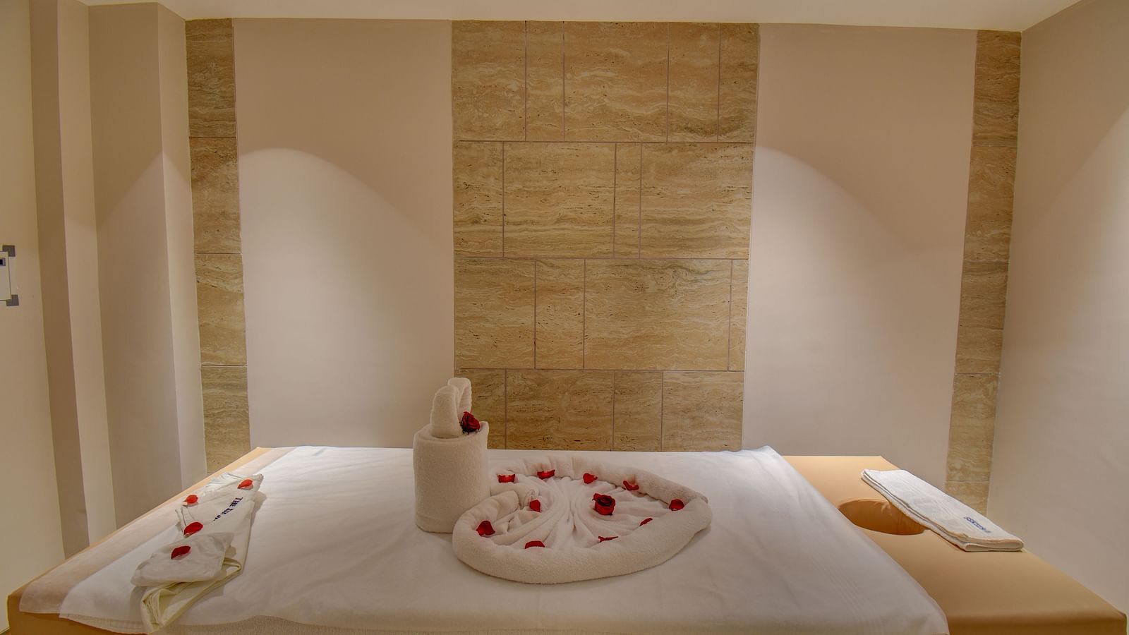 A Spa bed at  The SSK Solitaire Boutique Hotel & Spa, Gangapur Road - Nashik featuring a towel in heart shape and flower petals.
