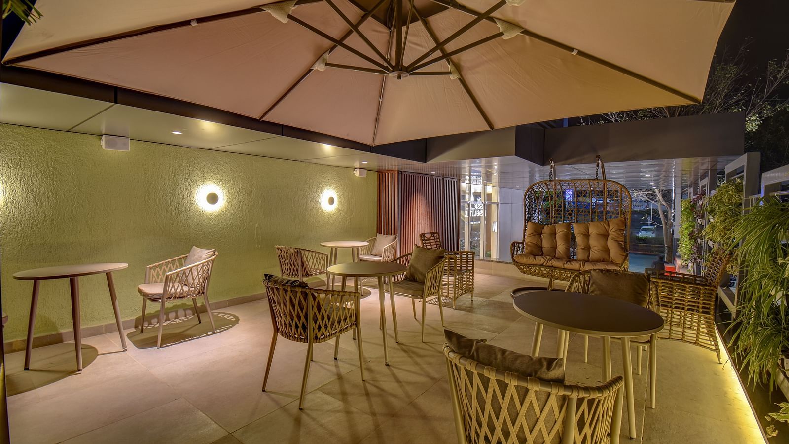 Overview shot of seating area of a restaurant with table and chairs on a terrace with swing |The SSK Solitaire Boutique Hotel & Spa, Gangapur Road - Nashik