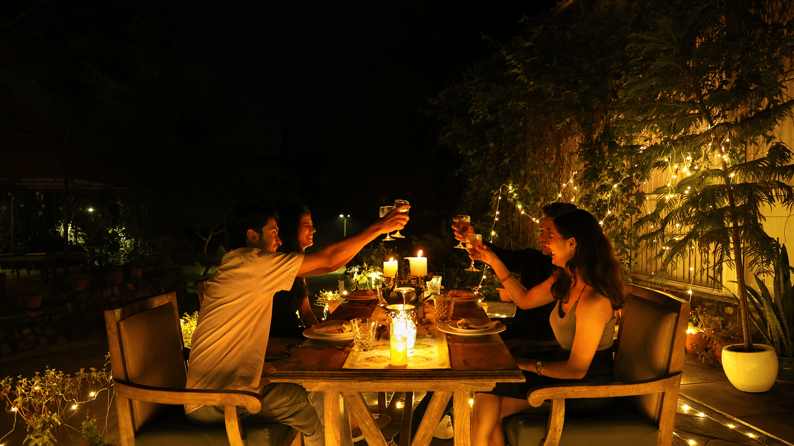 A lavish open-air dining setup with people enjoying a meal  at night at The Sylvan Retreat, Dehradun.