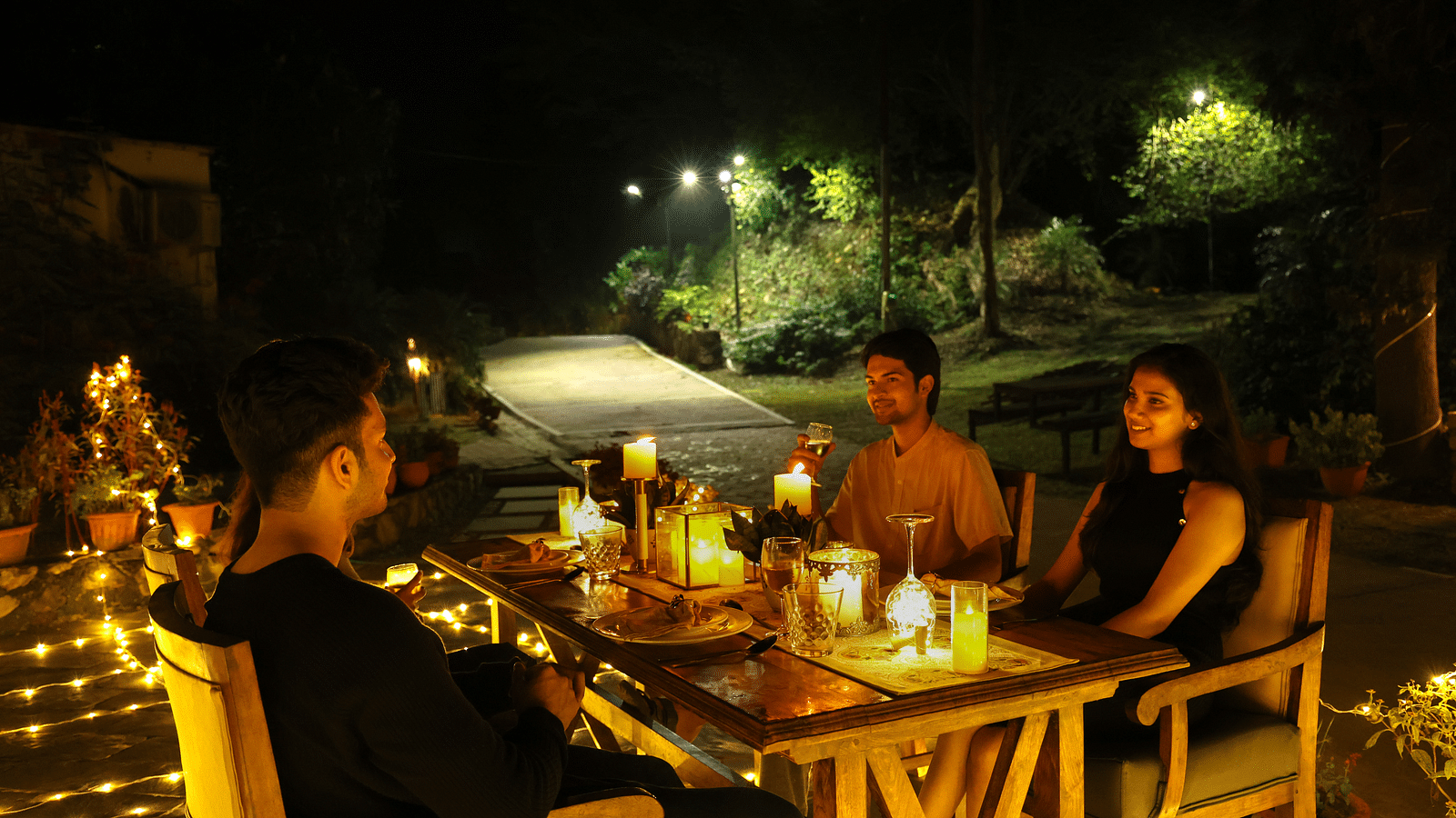 A lavish open-air dining setup with people enjoying a meal at night at The Sylvan Retreat, Dehradun.