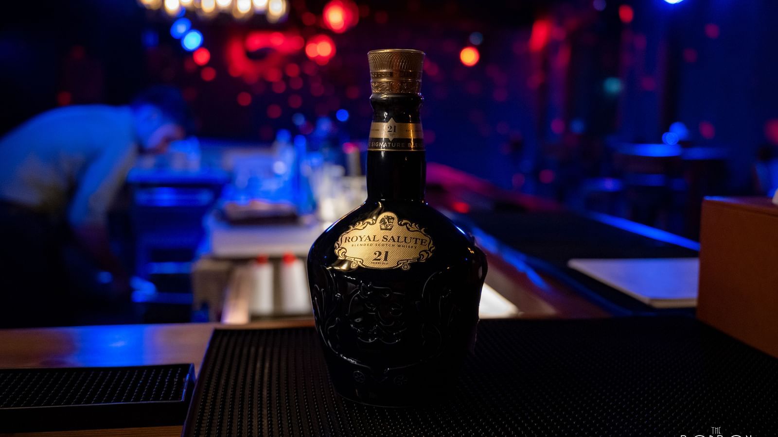image of a beautiful liquor bottle kept in a dimly lit bar with blue lights - The Tattva Boutique Resort