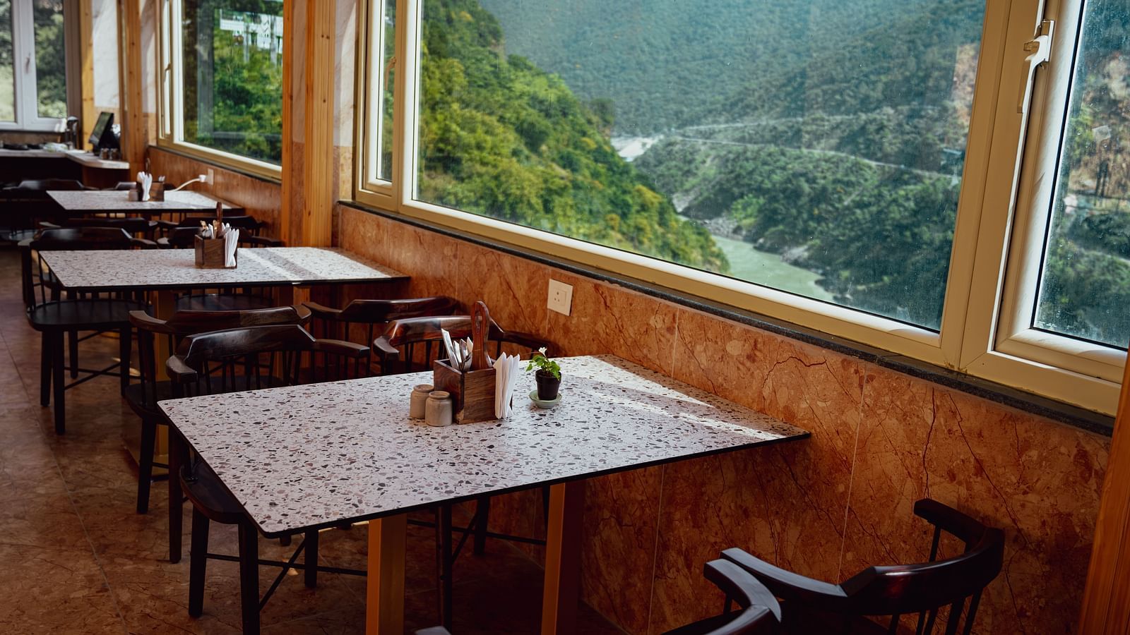 Image of the dining area by the window overlooking the mountains and the river | The Tattva Devprayag