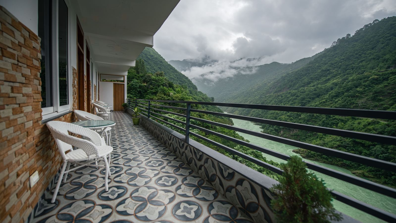 A balcony of a Deluxe Room at The Tattva Devaprayag with a view of the mountains and the river.