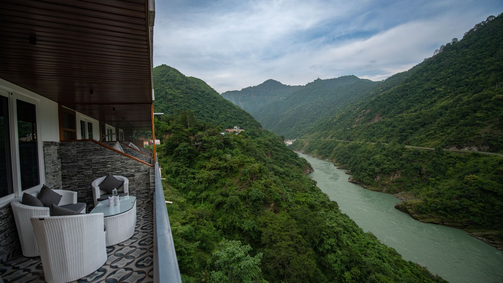 A balcony in the executive room at The Tattva Devaprayag with a view of the mountains and the river.