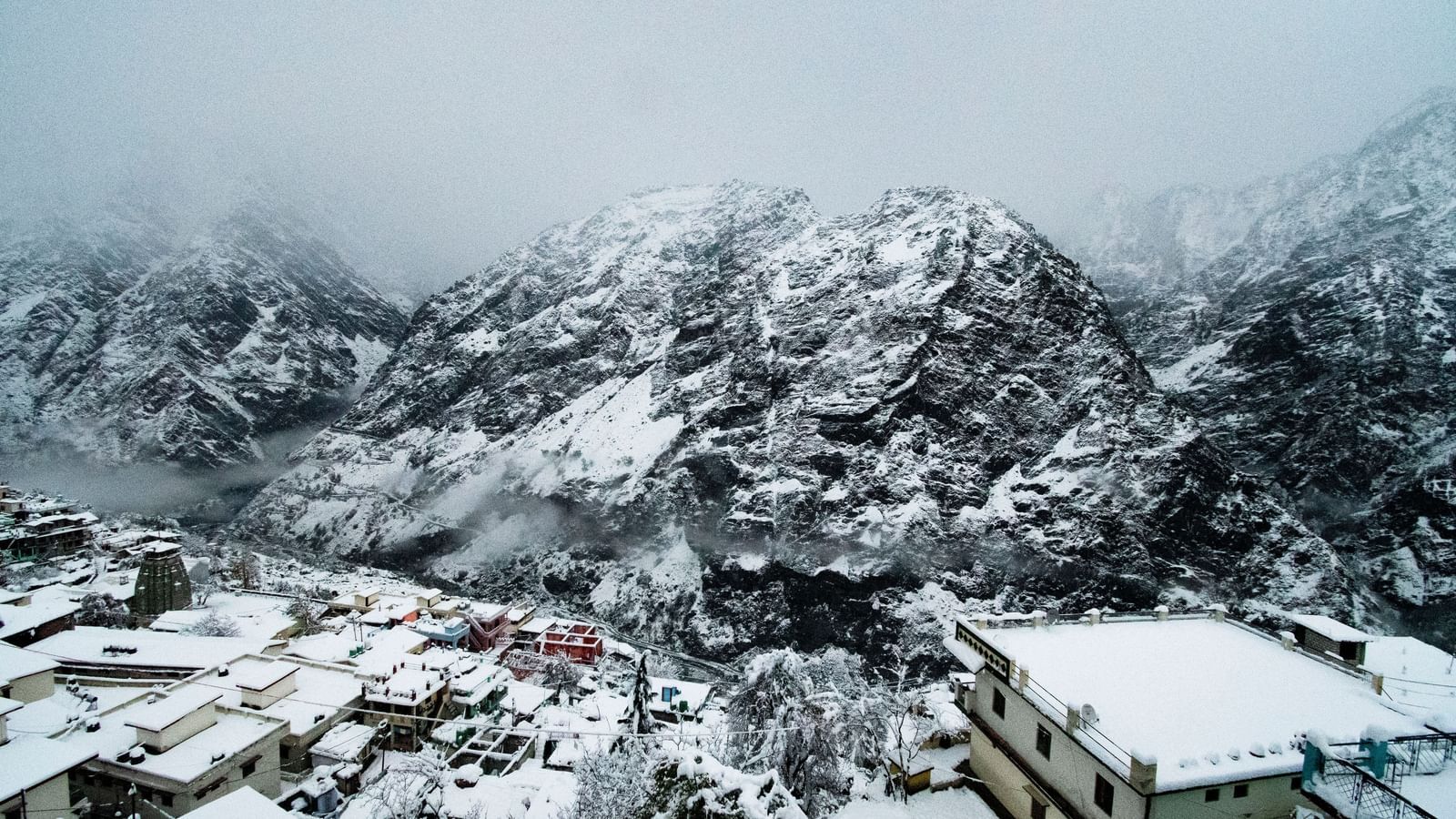 Mountain peaks covered with snow and mist  with small houses in the foothills