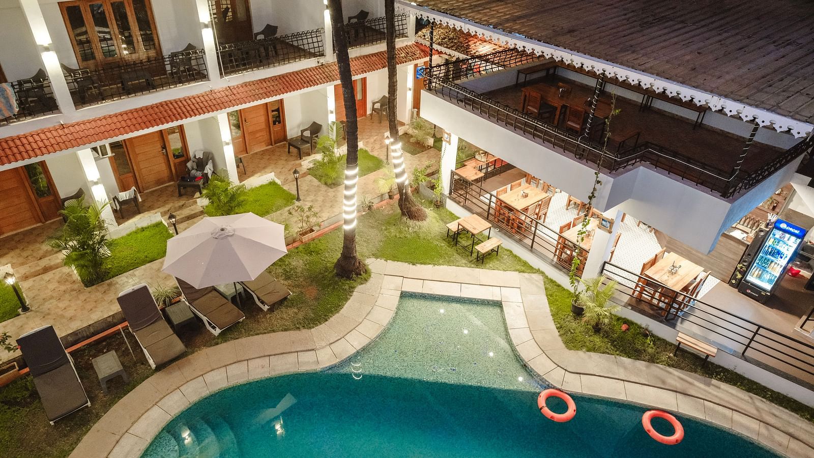 Aerial view of the swimming pool surrounded by sun loungers and palm trees at The Verda de Miranda Resort.