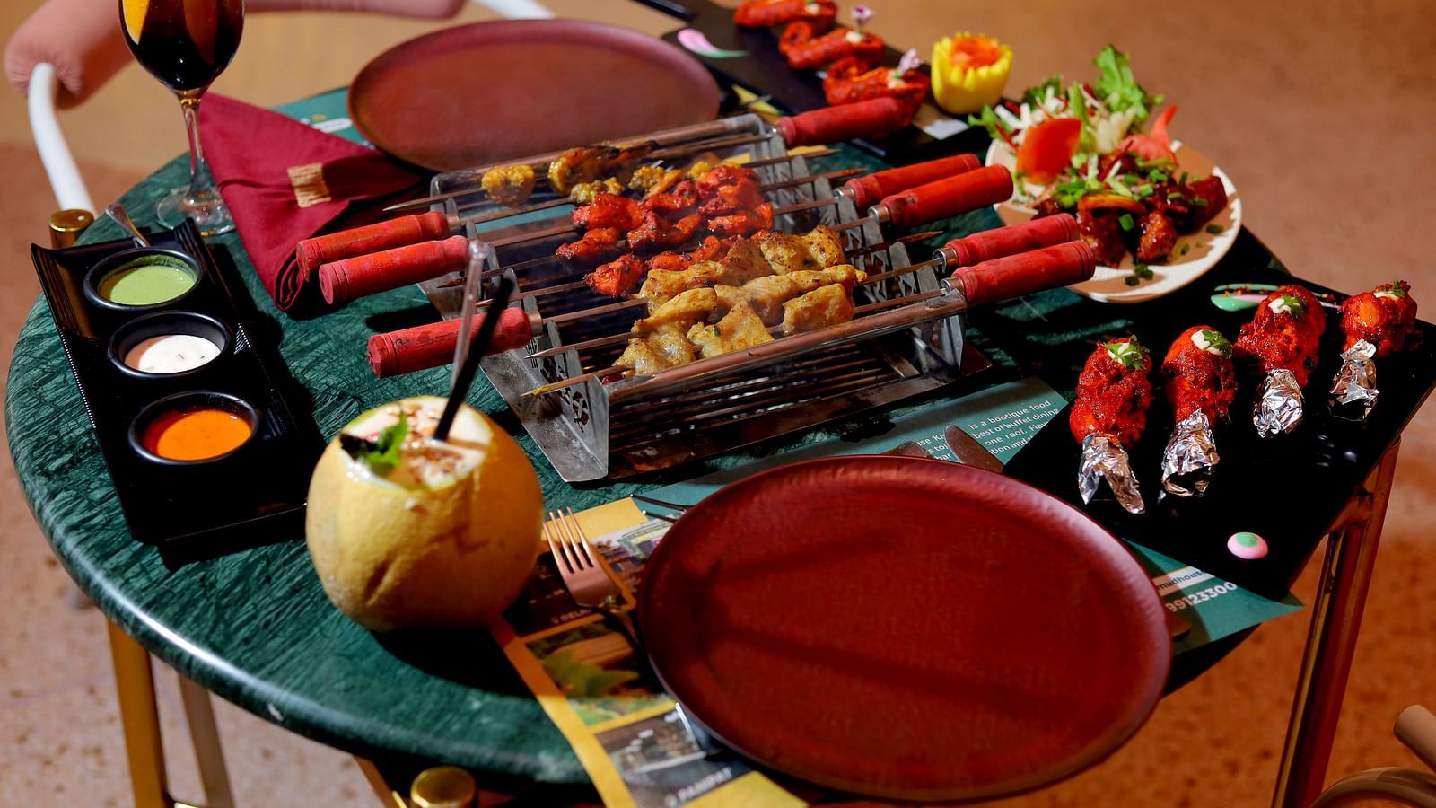 An image of a barbecue table where several eatables are placed like grilled meat, spices, condiments, sauces, dishes, etc at Themis Barbecue House, Ambala