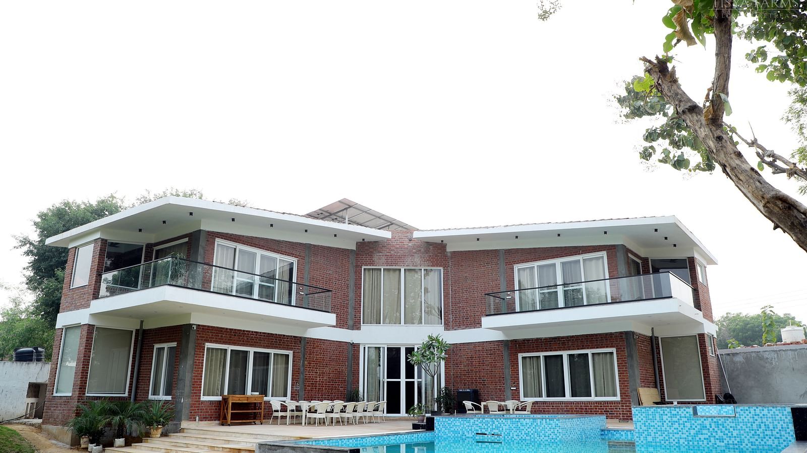 Facade image of Tisya Farms, Gurgaon surrounded by lush greenery.