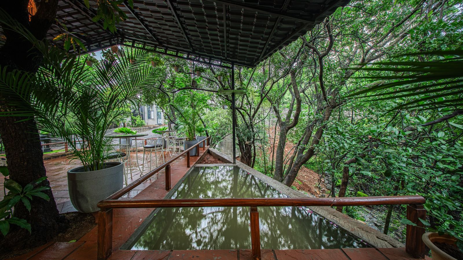 A covered outdoor walkway with a tiled floor and a reflection pond, surrounded by lush green foliage - Tranquil Piedmont Estates & Resort