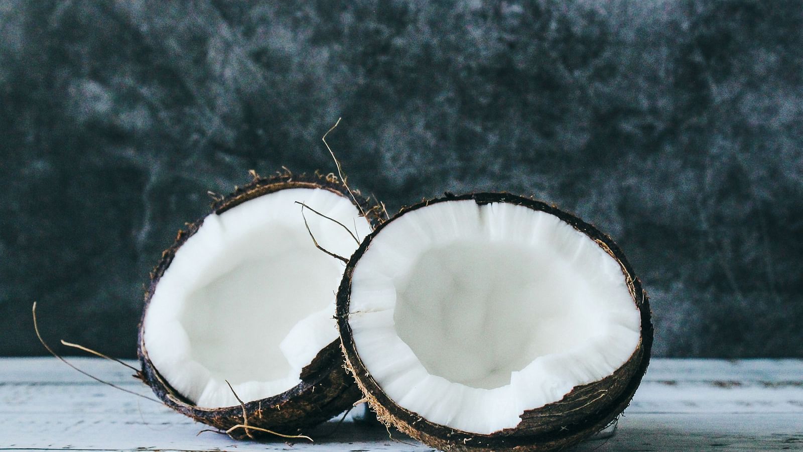 A close up shot of a coconut split into two and kept on a table.