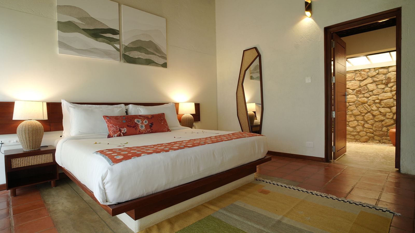  A well-appointed bedroom at Vaasta Vagamon featuring a large bed, bedside tables with lamps, a floor-length mirror, and artwork.