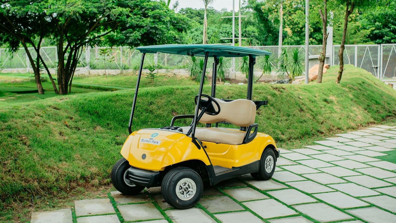 An E-cart parked neared a lawn space, surrounded by lush green foliage.