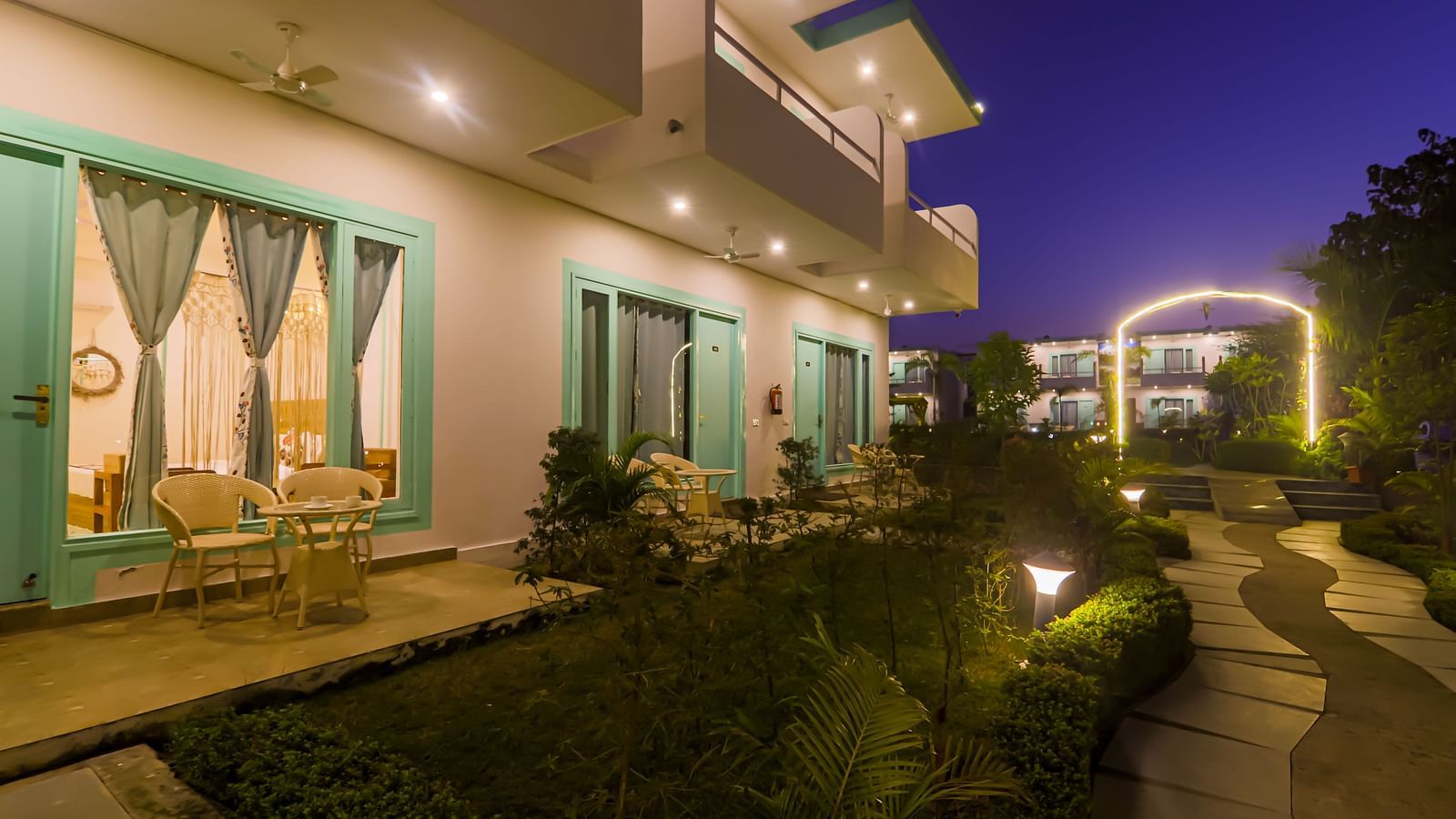 Balconies of rooms at Vedikant Resorts The Mallard Corbett are lit up at night, overlooking the grounds.