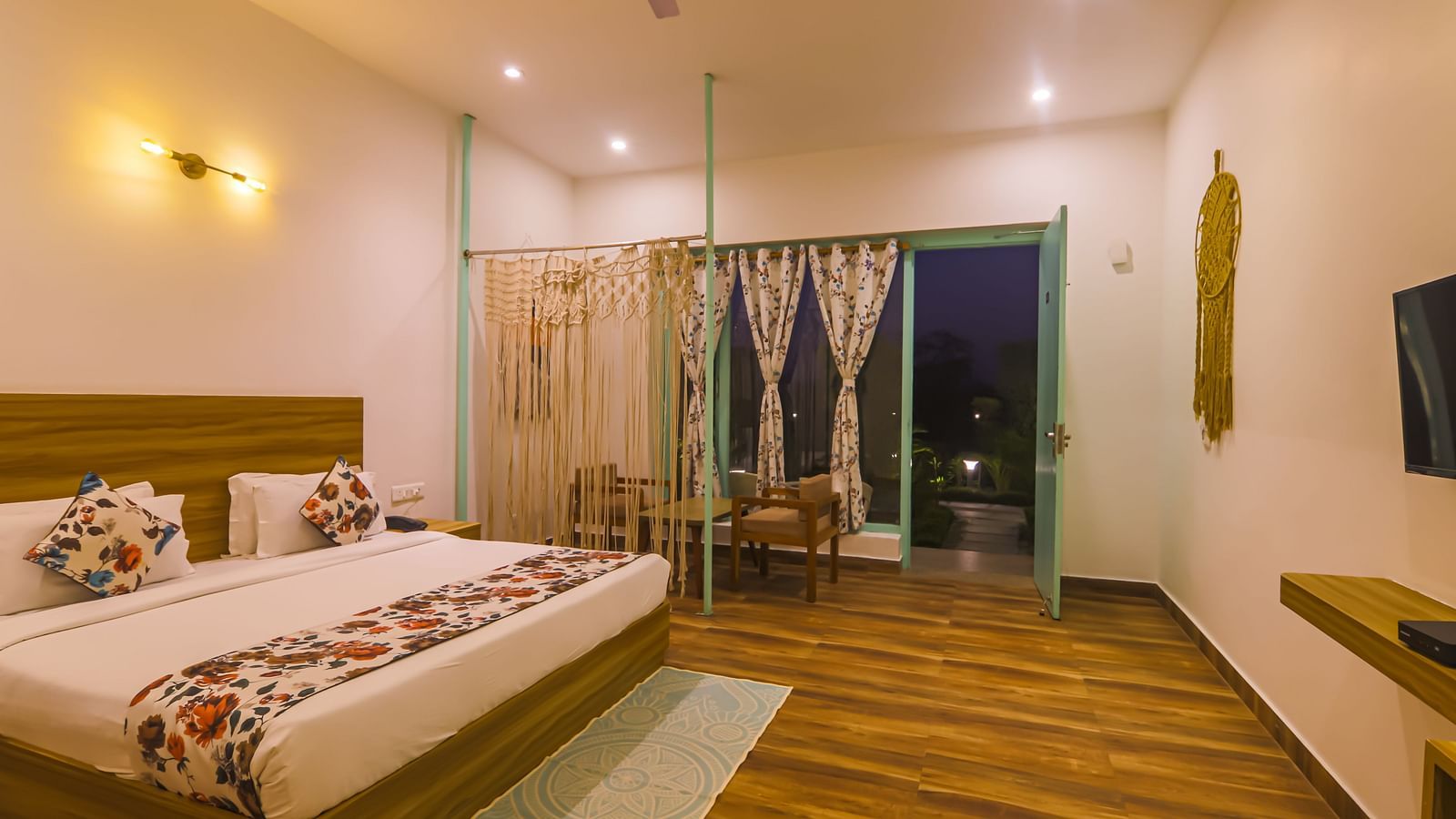 A well-lit bedroom at Vedikant Resorts The Mallard Corbett features a bed, seating area, and open balcony doors.