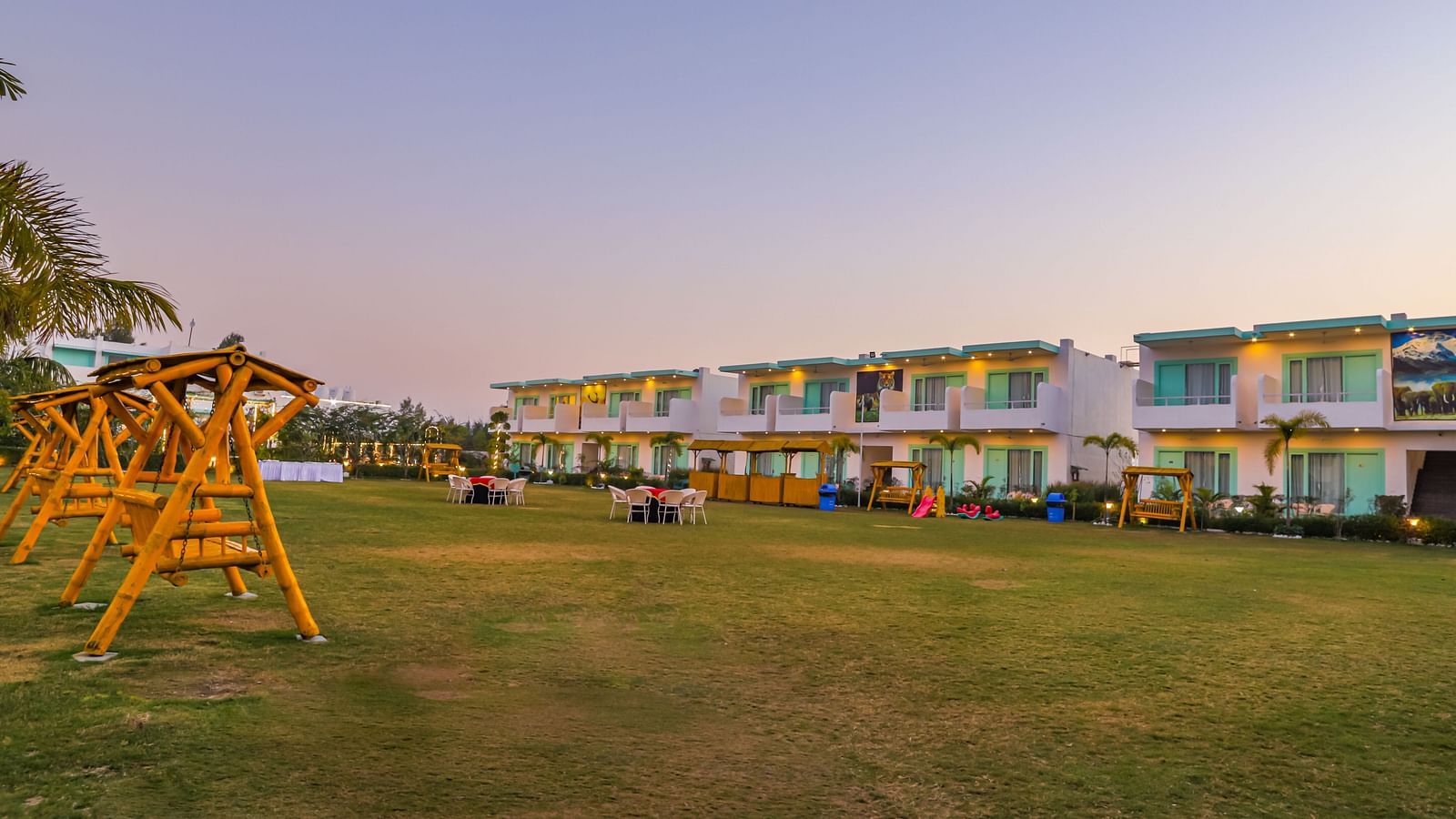 Daytime view of the garden setup with a wooden swing and lawn seating at Vedikant Resorts The Mallard Corbett.