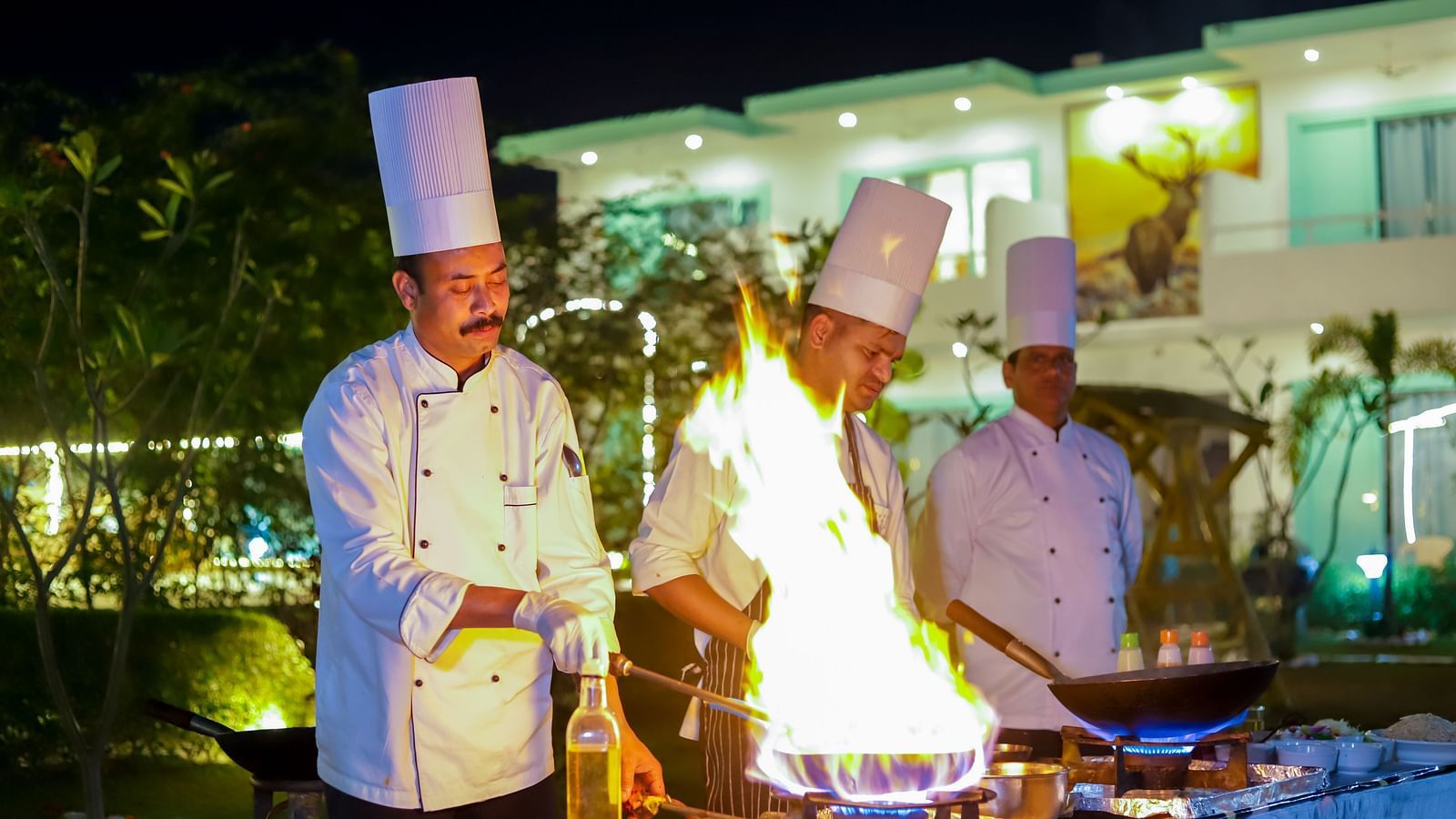 Vedikant Resorts The Mallard Corbett chefs performing a live cooking session with flames rising from the grill.