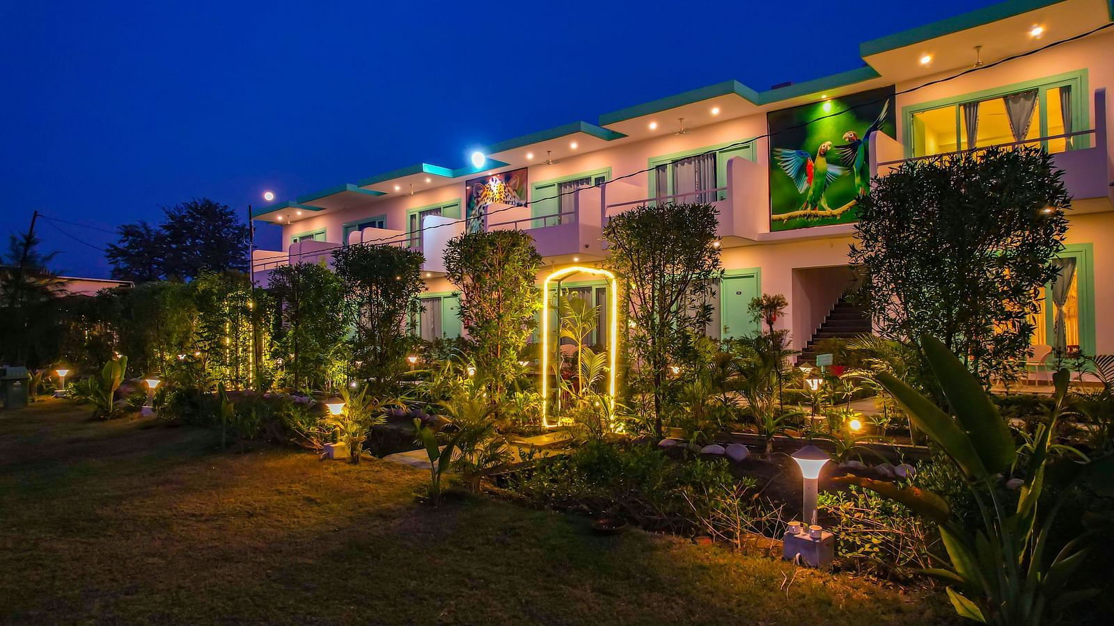 Night view of a walkway and entry arch at Vedikant Resorts The Mallard Corbett with garden plants and warmly lit building facade.
