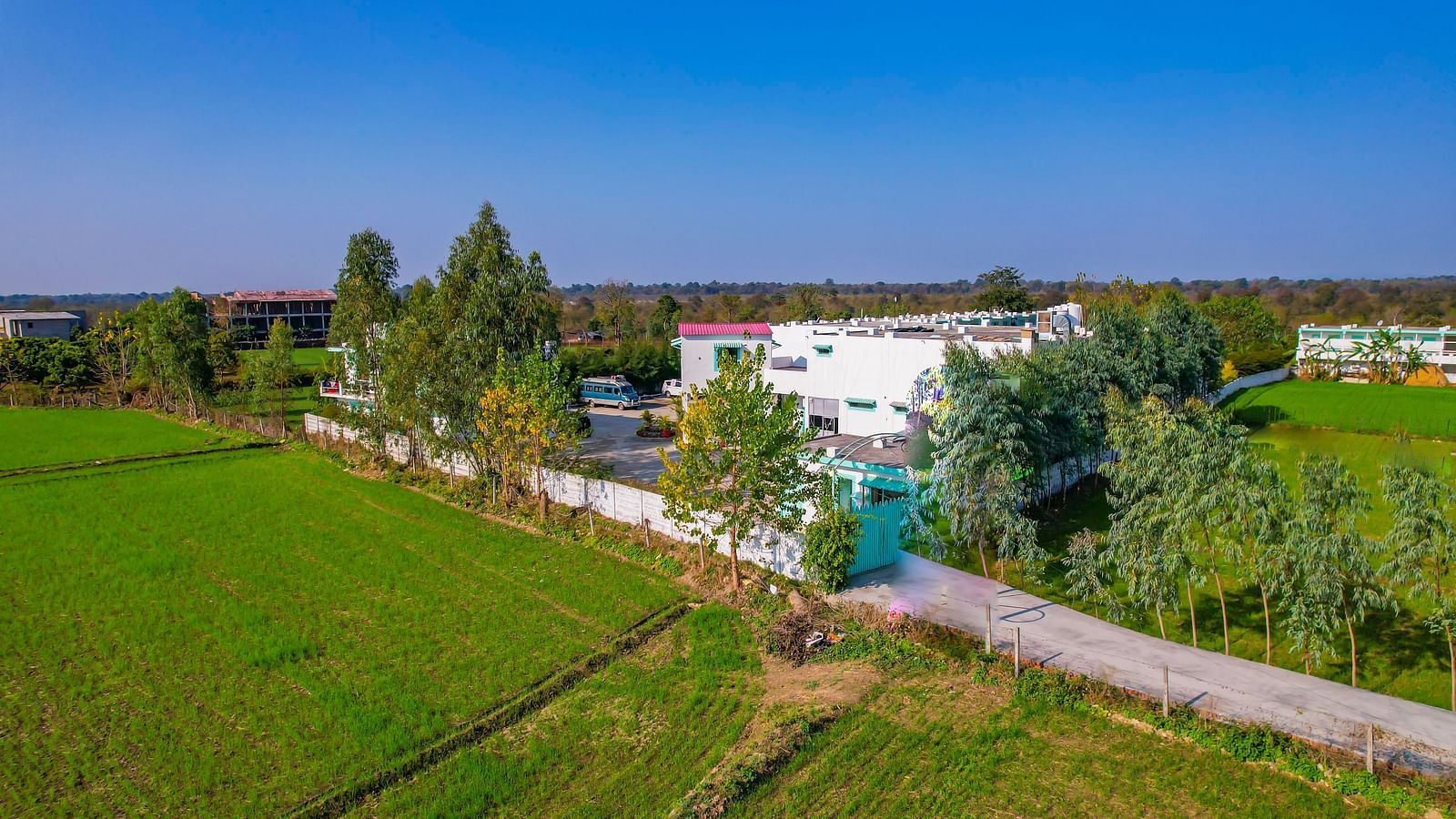 Aerial view of the resort surrounded by farmlands and forests, showing its peaceful location in Corbett.