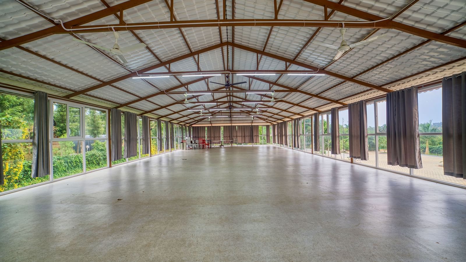  A large, empty hall with a high, exposed truss ceiling and a light-coloured concrete floor, possibly a banquet or event space. - Vintage Trails by Ilara