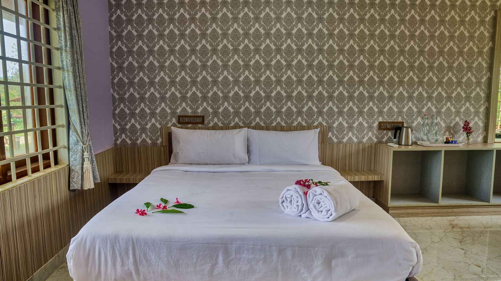  A bedroom with a large white bed against a textured, light-coloured wall, with a small bedside table, ready for guests. - Vintage Trails by Ilara