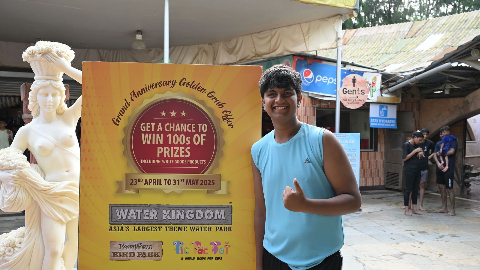 Guest posing with the event banner of the Golden Grab Celebration at Water Kingdom.