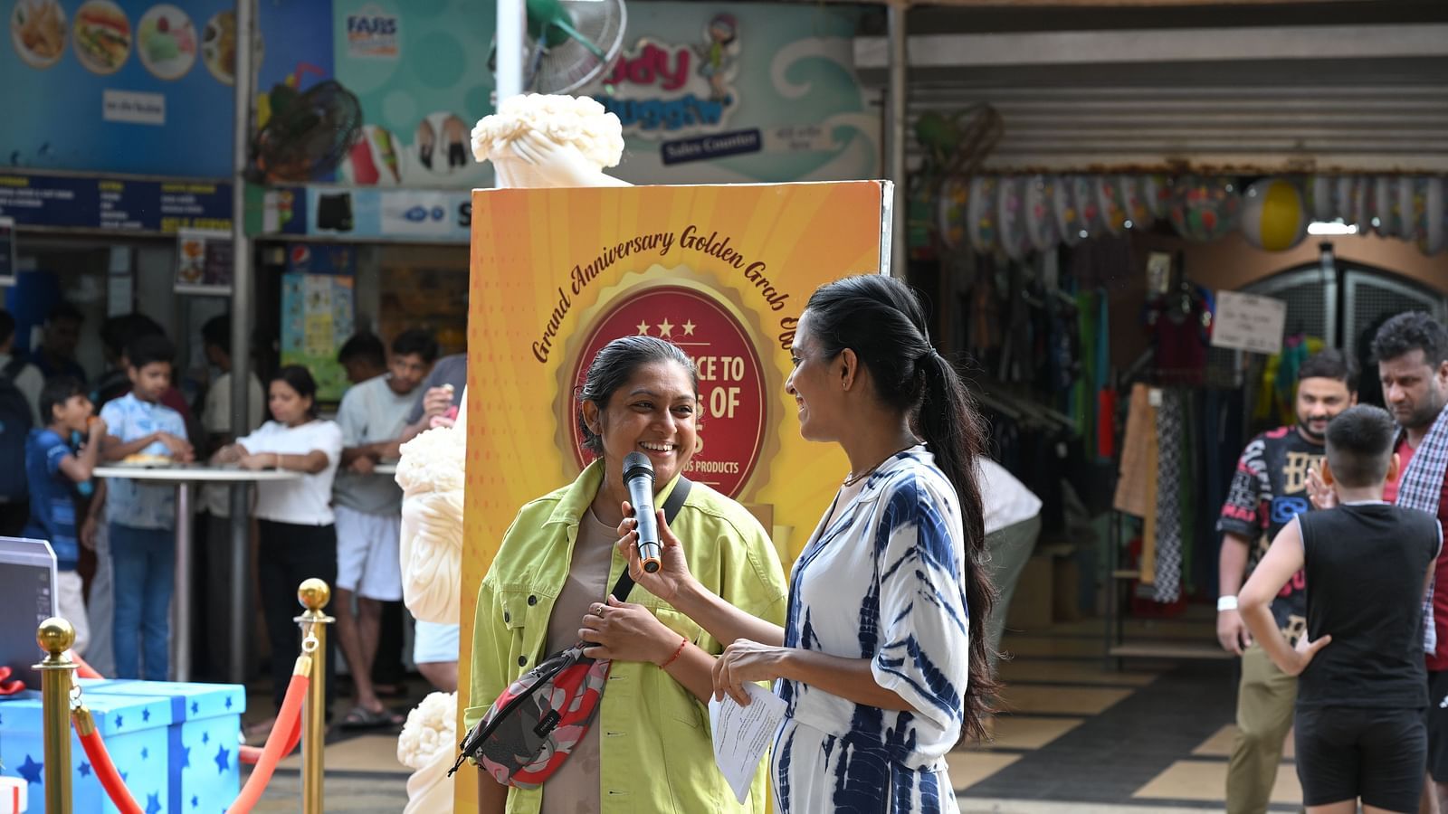 Two women sharing a light moment on stage during the Water Kingdom event.