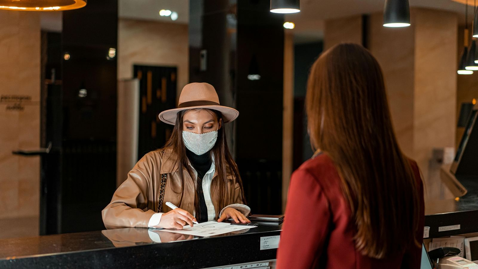 View from the reception of a person writing with the receptionist behind the counter.