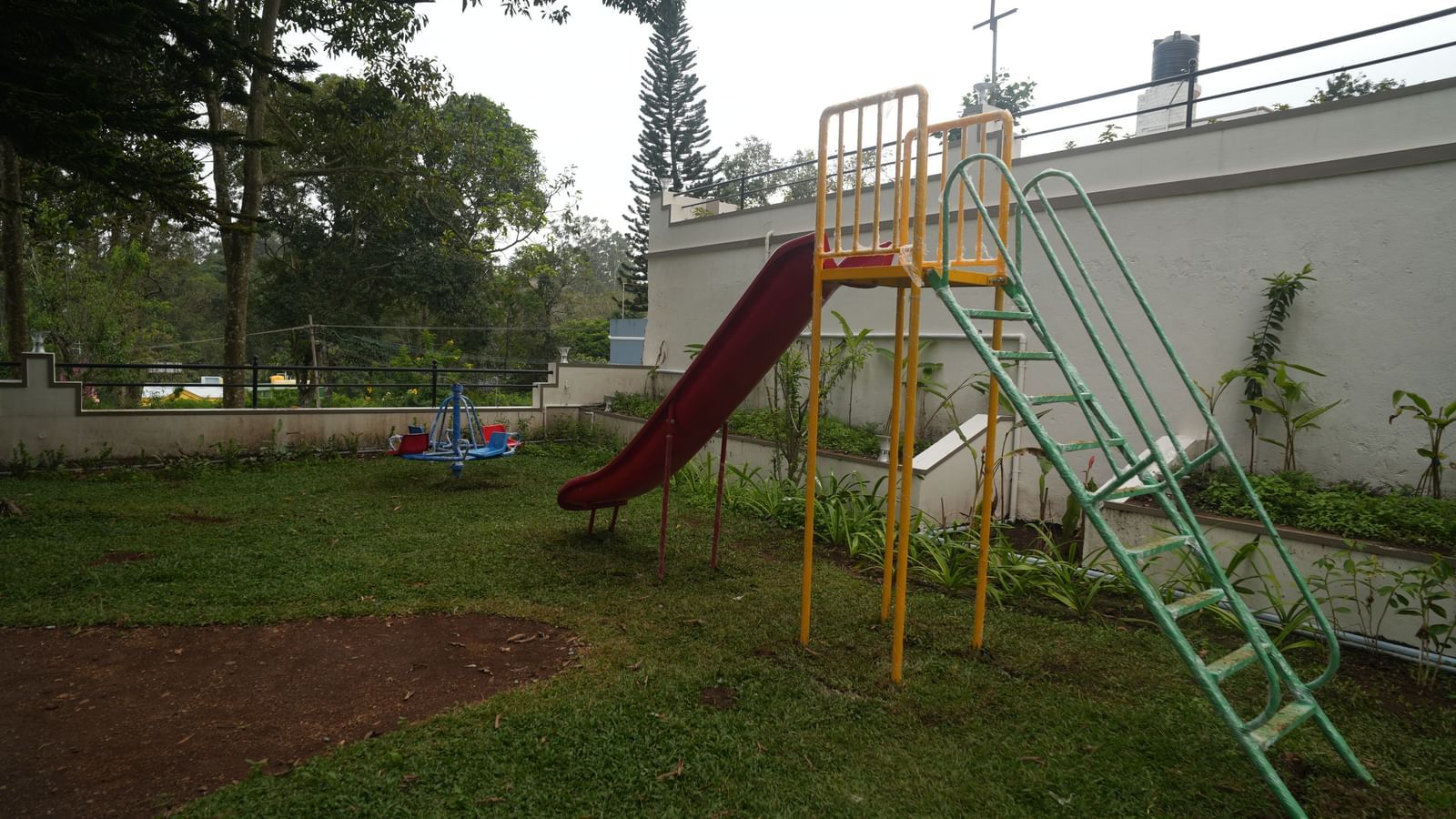 A slide in a garden at the WOW Naturefull Resorts surrounded with lush green trees.