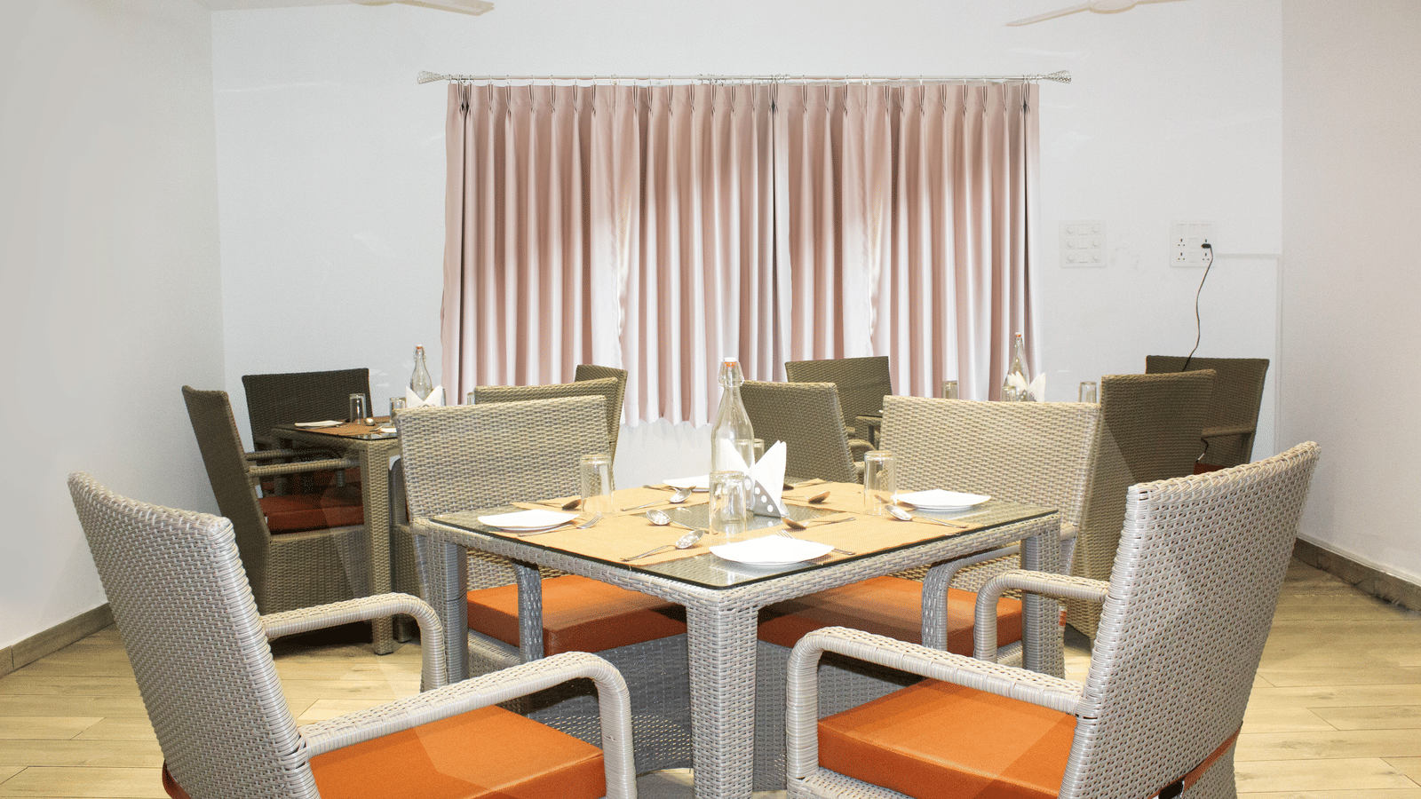 A dining table with orange-coloured cushions on the chair at the Spice and Slice Restaurant at WOW Naturefull Resorts, Yercaud.