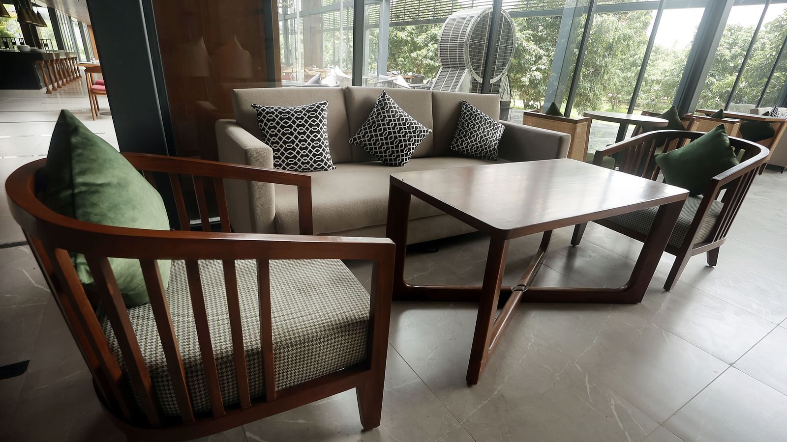 Bar area featuring a wooden sofa set with neutral-toned cushions near expansive windows at Wyndham Garden.