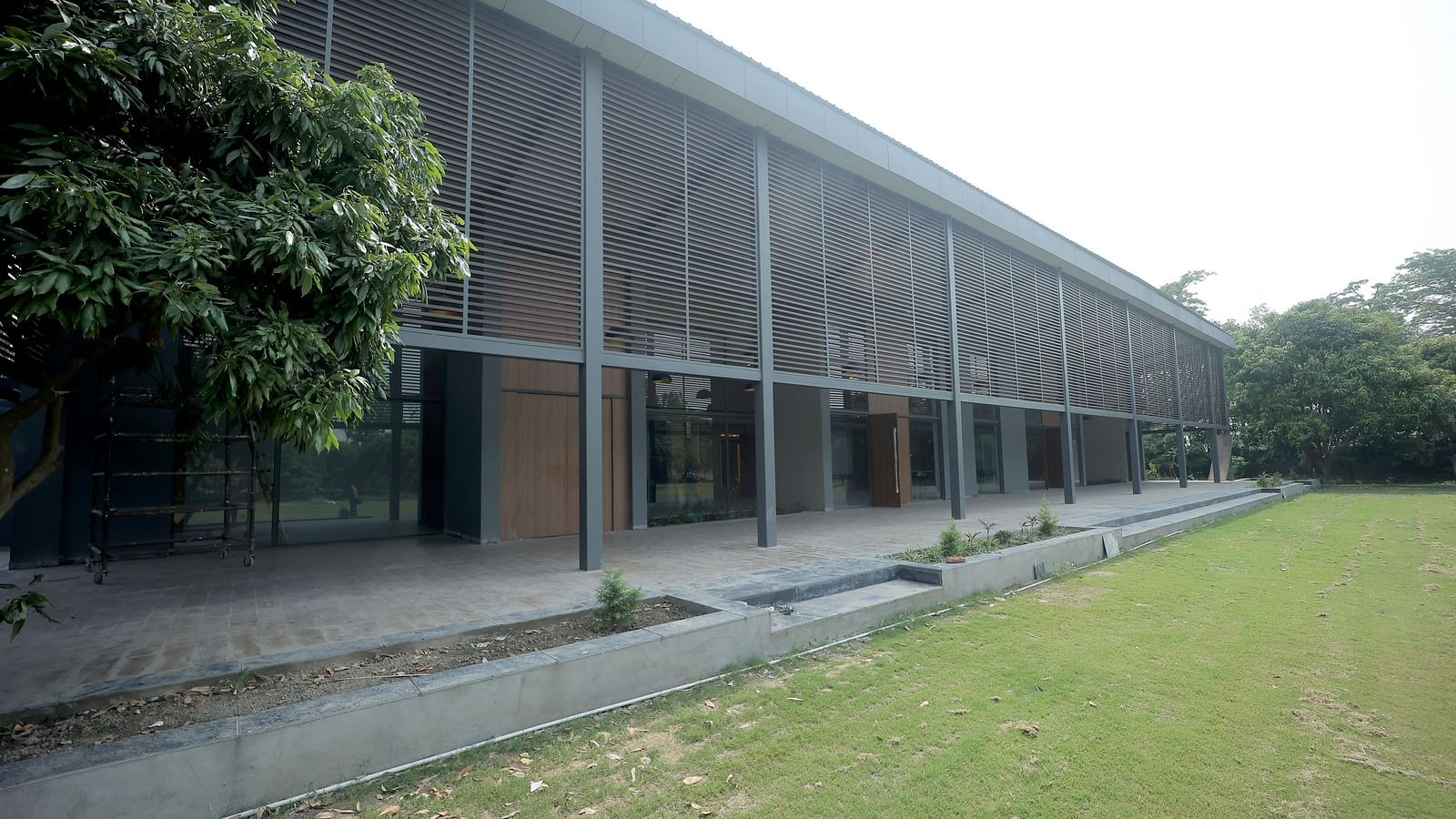 Modern building façade with large glass windows facing a well-kept lawn and trees at Wyndham Garden.