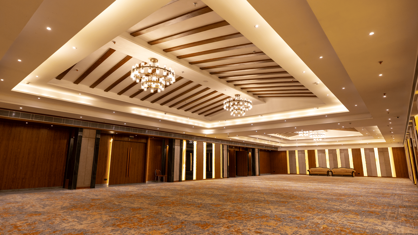 An illuminated banquet hall at Wyndham Garden with a layered ceiling design and an open floor space.