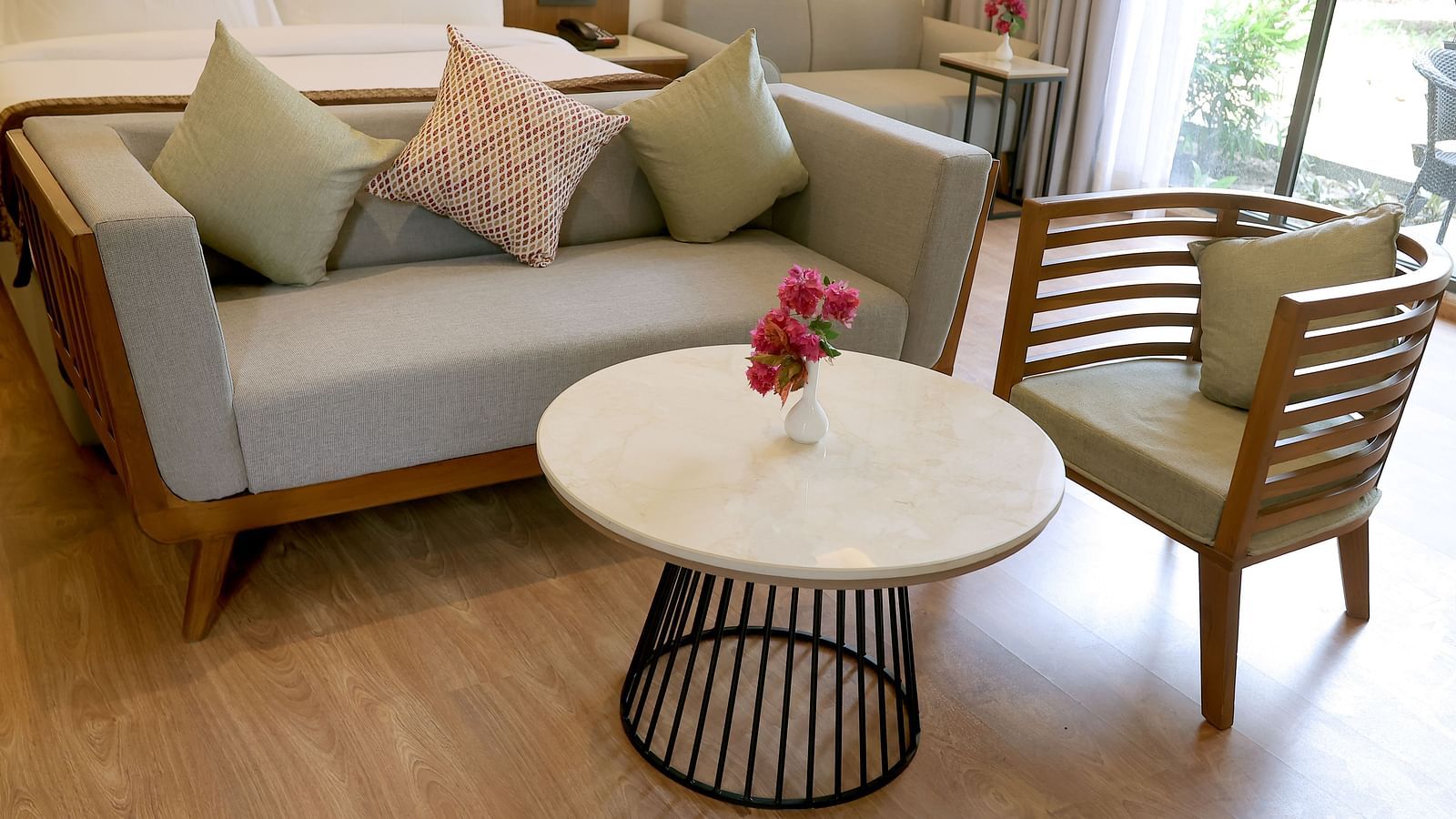 Close-up of a stylish seating area with pastel cushions and a round table set with flowers at Wyndham Garden.