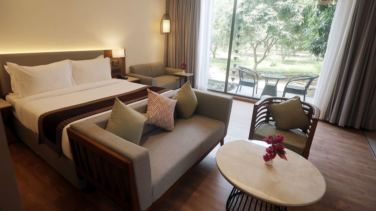 Cosy bedroom with outdoor views, soft grey curtains, and a plush bench at the foot of the bed at Wyndham Garden.
