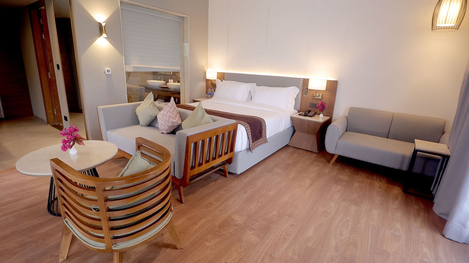 Elegant room with a king size bed, grey settee, two stylish chairs, and wooden flooring at Wyndham Garden.