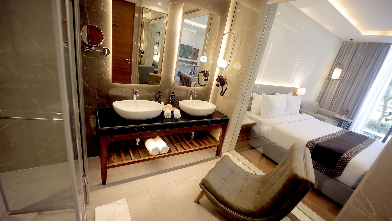 Modern bathroom with dual basins, a vanity mirror, and a view into the bedroom area at Wyndham Garden.