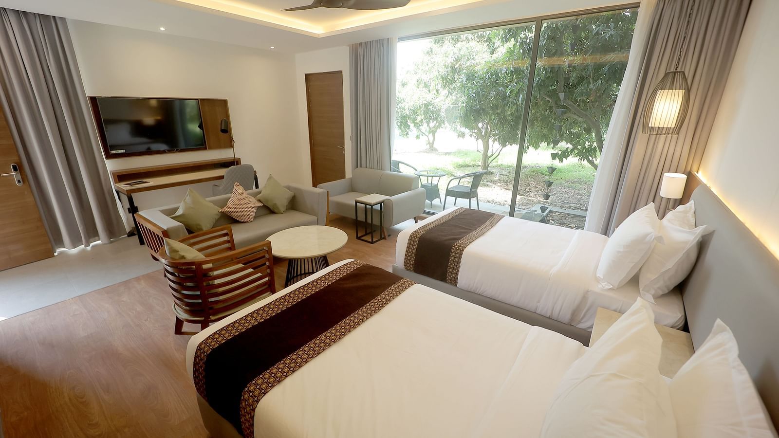 Bright twin room with flat-screen TV, dual chairs, and a view of green lawns through large windows at Wyndham Garden.