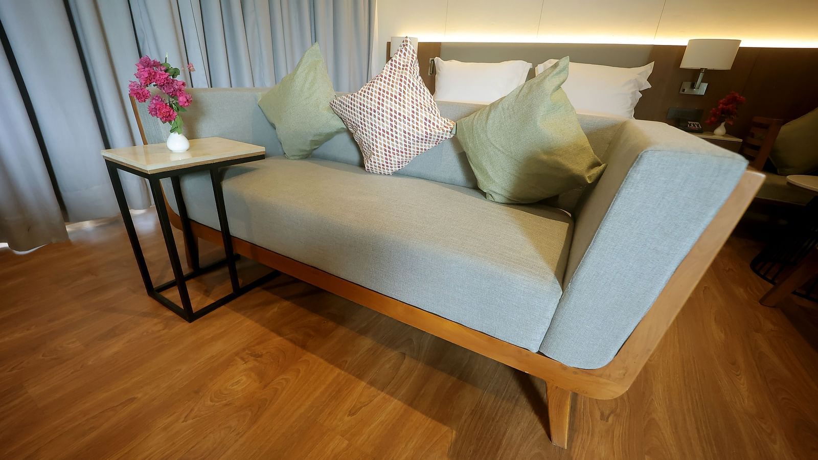 Stylish corner with a powder blue upholstered chaise lounge, cushions, and a side table on wooden flooring at Wyndham Garden.