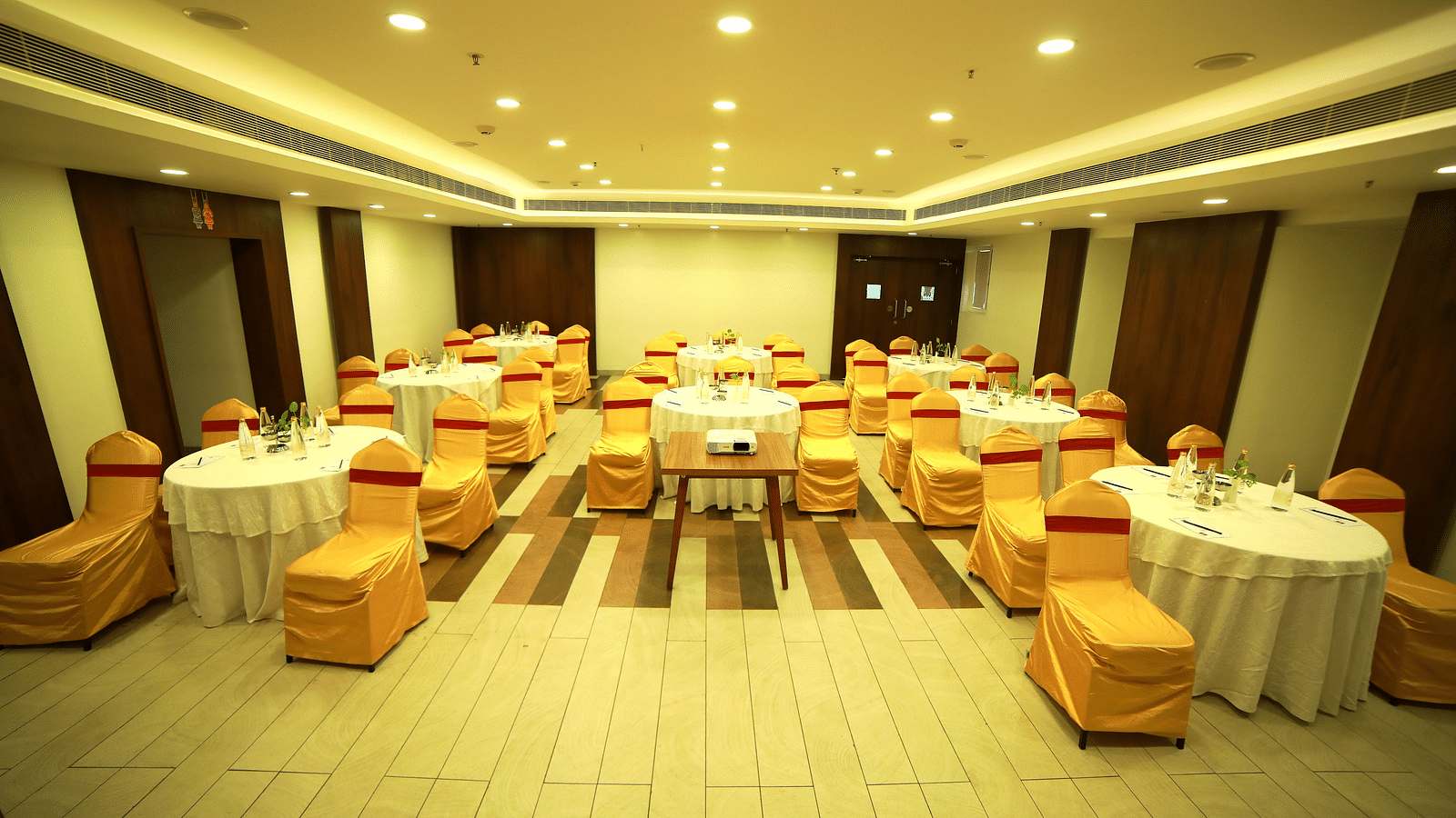 A spacious event hall with elegant ceiling lights illuminating the room at Zibe Salem by GRT Hotels