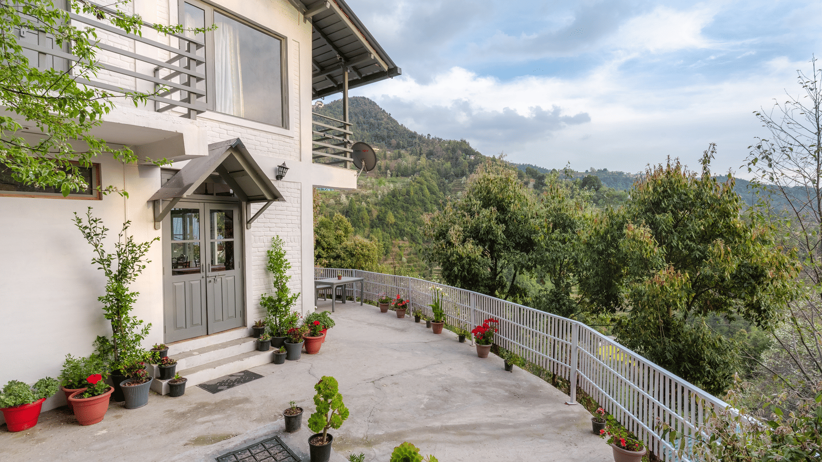 An exterior shot of the Ziran Retreat building, showing the white house with a sloping road in front and a mountain view in the background.