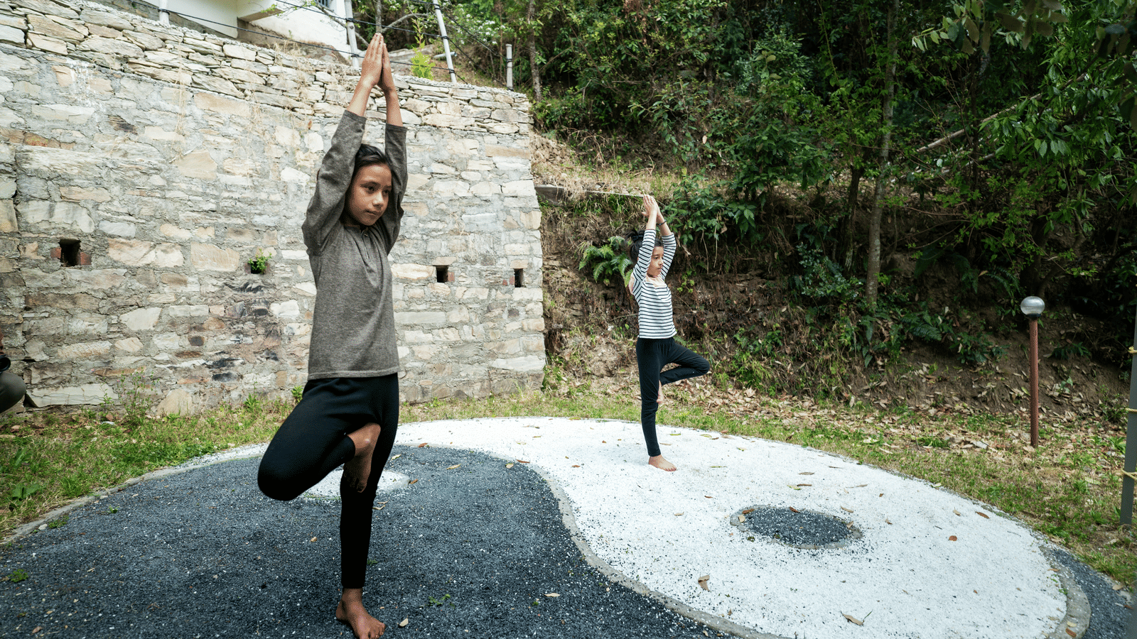 Two people are doing a tree pose on a yin-yang symbol at Ziran Retreat.