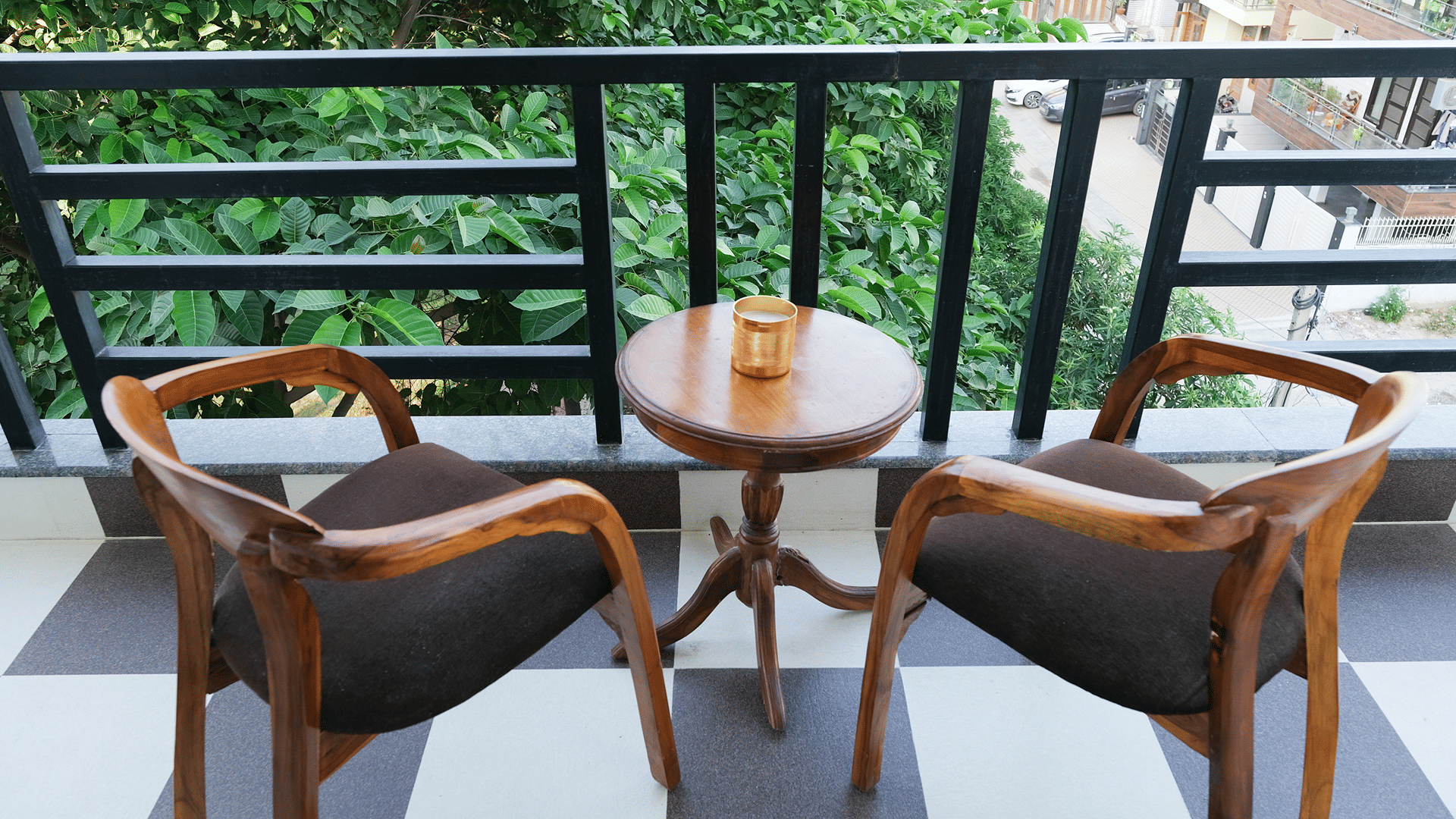 Balcony of Lime Tree Hotels & Service Apartment Private Limited featuring wooden chairs, a round table, and a checkered floor.