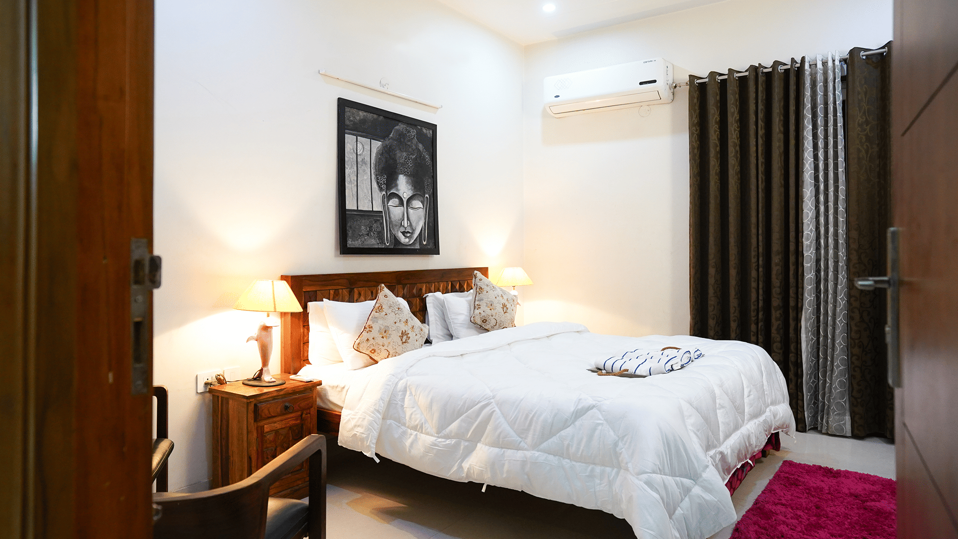 Bedroom of Lime Tree Hotels & Service Apartment Private Limited featuring a framed portrait artwork, white bedding, and a red rug.