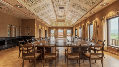 A large meeting room with a U-shaped wooden table in the centre and chairs under it at AamaGhati Wildlife Resort - best Destination Wedding in Ranthambore.