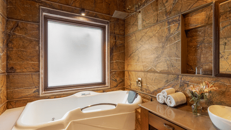 The living room area with a flat-screen television and a dining table at Aamaghati Wildlife Resort.