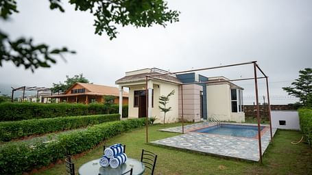 Facade of an accommodation with an outdoor swimming pool and a seating area beside it at Aanandam Resort & Spa, Pushkar.
