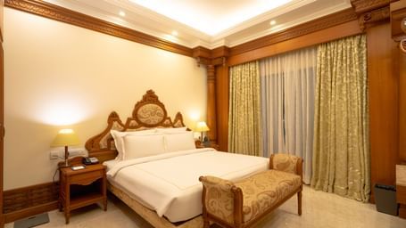 Hotel room with a king size bed, bedside tables, and curtains.