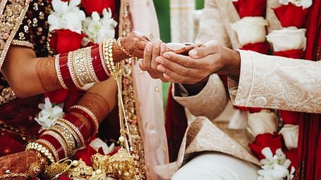 Close-up view of the bride and groom holding hands, both in wedding attire.